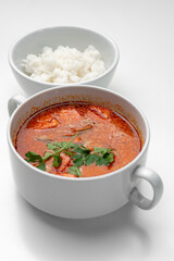 Bowl of curry with pieces of meat and a side of steamed rice arranged neatly for a meal