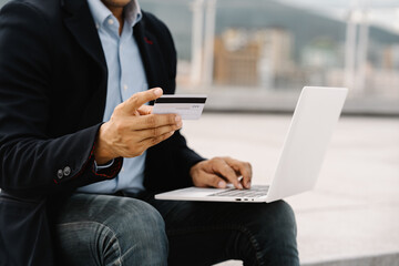 Online Shopping Man: Close-up of a businessman's hands, confidently making an online purchase with his credit card and laptop, symbolizing the ease and convenience of modern e-commerce.  