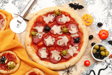 Composition with tasty Halloween pizzas, cutter and decorations on grunge background
