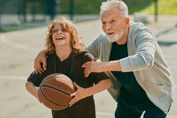 Grandfather teaching grandson basketball outdoors