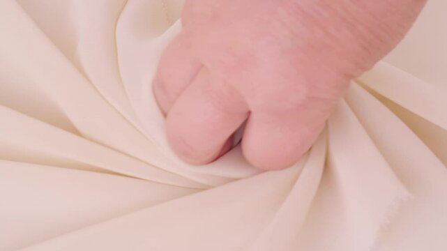 Female hands inspecting silk texture and quality delicate chiffon, crepe, hand feels sensual tactile pleasure, testing for durability, stretch and crease resistance