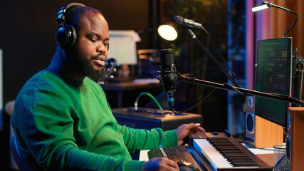 Professional artist writes new verses for a song in home studio, producing new music with mixing...