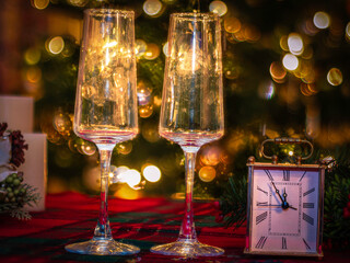 two toasting champagne glasses and countdown clock  on glittering background, happy new year  celebration