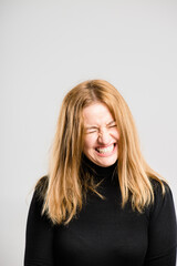 Naklejka premium Funny, face and woman in studio space with smile, comedy and happy aesthetic style with mockup. Laughing, crazy fun and person with positive attitude, joke and casual fashion on white background.