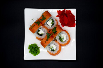 Prepared sushi rolls on a white plate on a black background