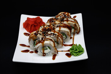 Prepared sushi rolls on a white plate on a black background