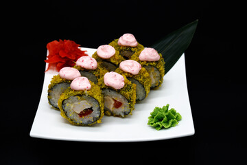 Prepared sushi rolls on a white plate on a black background