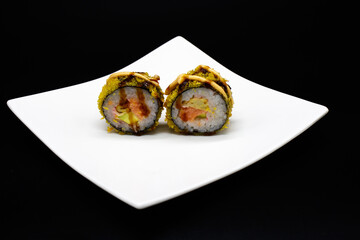 Prepared sushi rolls on a white plate on a black background