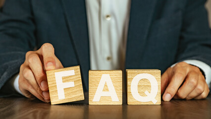 There is wood cube with the word FAQ. It is an abbreviation for Frequently Asked Questions as...