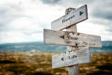 reset your life text quote on wooden directional signpost outdoors in nature