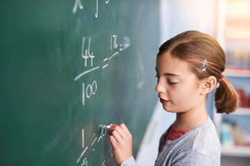 Little girl, writing and mathematics with chalkboard in classroom for education, learning or...