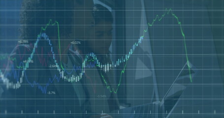 Financial data and stock market graph image over business professionals working on laptop