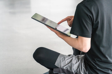 タブレット端末を使うスポーツウェア姿の若いアジア人男性
