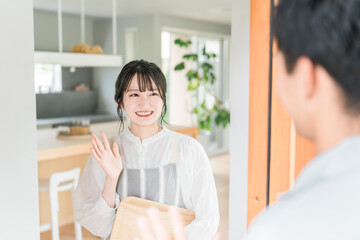 Obraz premium 朝出勤する夫・旦那を笑顔で見送りする若いアジア人女性・妻 