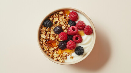 a bowl of fresh granola with greek yogurt topped with honey and fresh berries against an isolated light beige background