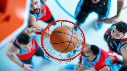 Dynamic overhead shot of basketball players focused on the game as the ball approaches the hoop in an intense moment.
