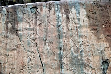 Ancient petroglyphs depicting human figures on a rock surface.