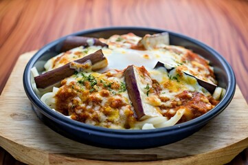 A delicious baked pasta dish topped with cheese and eggplant, served in a round dish.