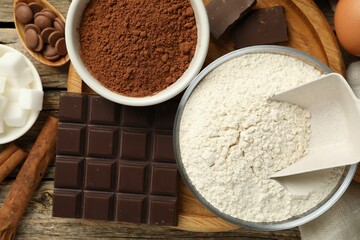 Flour, chocolate and cocoa for making dough on wooden table, flat lay