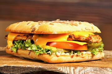 A delicious sandwich featuring grilled chicken, cheese, and fresh vegetables on a seeded bun.