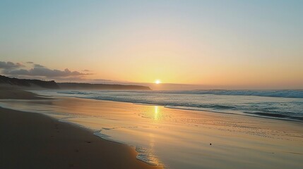 A beautiful beach under the natural sunset sky. The sand on the beach is golden, stretching out towards the ocean. The waves are gently lapping at the shore