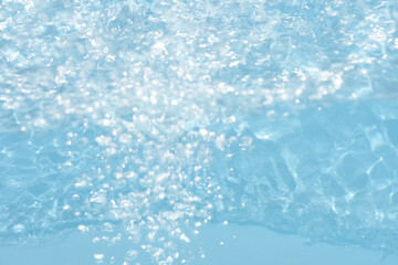 Blue water with ripples on the surface. Defocus blurred transparent blue colored clear calm water surface texture with splashes and bubbles. Water waves with shining pattern texture background.