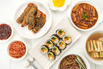 Assortment of Korean traditional dishes. Gimbap, tteokbokki, odeng, danmuji, kimchi, gimmari, jjangmyeon. Flat lay.
