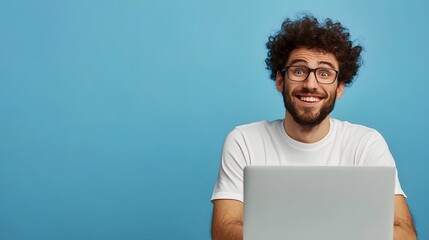 Happy man with curly hair wearing glasses and a white shirt smiling while using a laptop