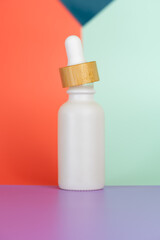 White oil dropper bottle with a bright color block background.