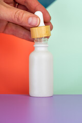 White oil dropper bottle with a bright color block background.