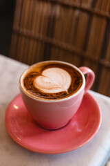 Cappuccino in a stylish pink mug side view. Delicious coffee with a beautiful latte art.