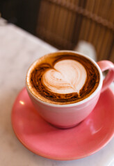 Cappuccino with a beautiful latte art in a pink cup close-up. The concept of delicious quality coffee