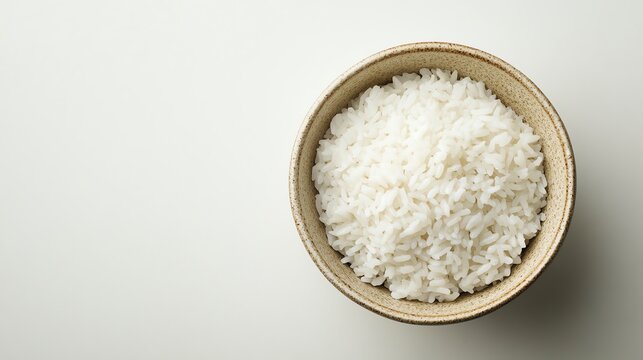 Top view of a bowl filled with freshly cooked white rice on a light background. Healthy food and diet concept.