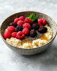 A bowl of oatmeal topped with raspberries, blackberries, chia seeds, and honey.