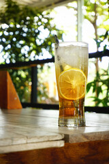 Refreshing iced drinks with lemon slices on a wooden table outdoors. Summer beverage concept.