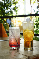Refreshing iced drinks with lemon slices on a wooden table outdoors. Summer beverage concept.