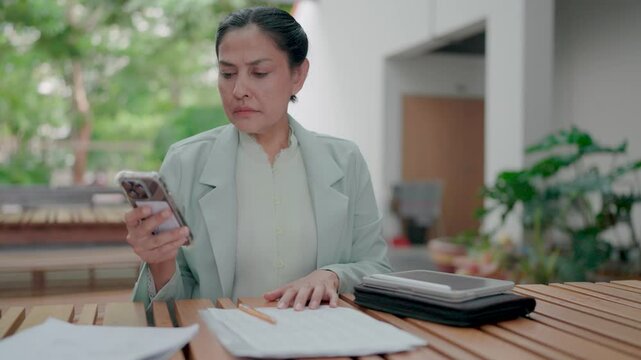 Frustrated businesswoman dissatisfied with work and answering incoming phone call and talking with dissatisfaction in outdoor. Working with tablet and taking notes. Deadline. Stress.