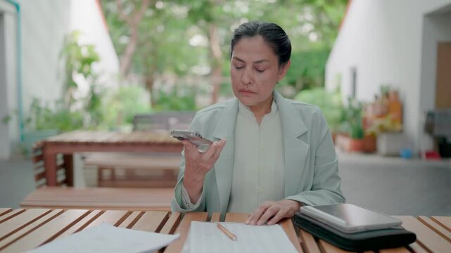 Answering the phone and speaking with dissatisfaction. Frustrated businesswoman dissatisfied with work and answering incoming phone call outdoors. Working on tablet and taking notes. Deadline. Stress