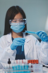 Group of dedicated scientist conduct chemical experiment in medical laboratory, carefully drop precise amount of liquid from pipette into test tube for vaccine drug or antibiotic development. Neoteric