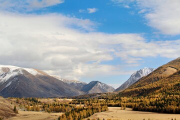 Scenic mountain landscape with autumn foliage and cloudy sky.