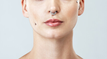 Piercings, lips and woman in studio with makeup, beauty and shiny gloss routine. Cosmetics, mockup space and closeup of female person with dermal filler injection for mouth by white background.