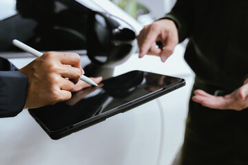 Insurance agent reviews car accident claim. Agent holds clipboard as customer signs form. Both discuss financial arrangements for damaged vehicle to ensure successful service.