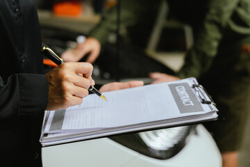 Car rental dealer is signing a rental contract with a professional salesperson. The agent will explain the details about car insurance and maintenance to ensure a smooth rental and service process.