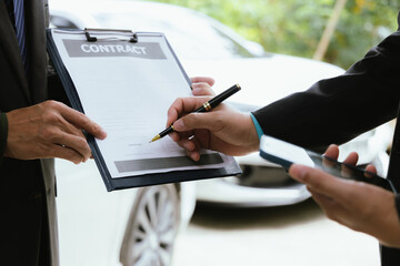 Car rental dealer is signing a rental contract with a professional salesperson. The agent will explain the details about car insurance and maintenance to ensure a smooth rental and service process.