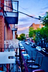 Metal balcony view down a tree-lined city street in early evening light