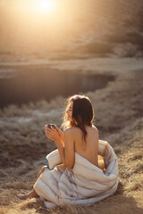 Serene Young Woman Enjoying Morning Coffee Wrapped in Blanket Outdoors