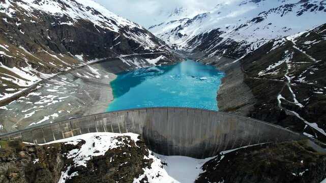 4k Drone Aerial Tilt Shot Of Vibrant Blue Glacial Water Of Lac de Moiry Dam Surrounded By Massive Snow Covered Mountains Reflecting On lake In Grimentz Switzerland