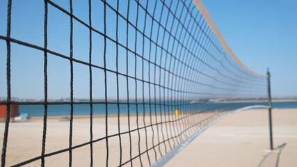 Volleyball net close-up and sand court on the seashore ready for play
