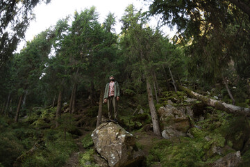 Fototapeta premium Man Standing on Rock in Forest: Nature Adventure and Exploration