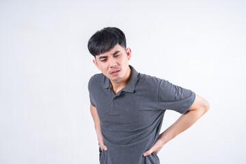 Portrait of handsome Asian man suffering from back pain due to lifting heavy objects. Medical and healthcare concept on white background.